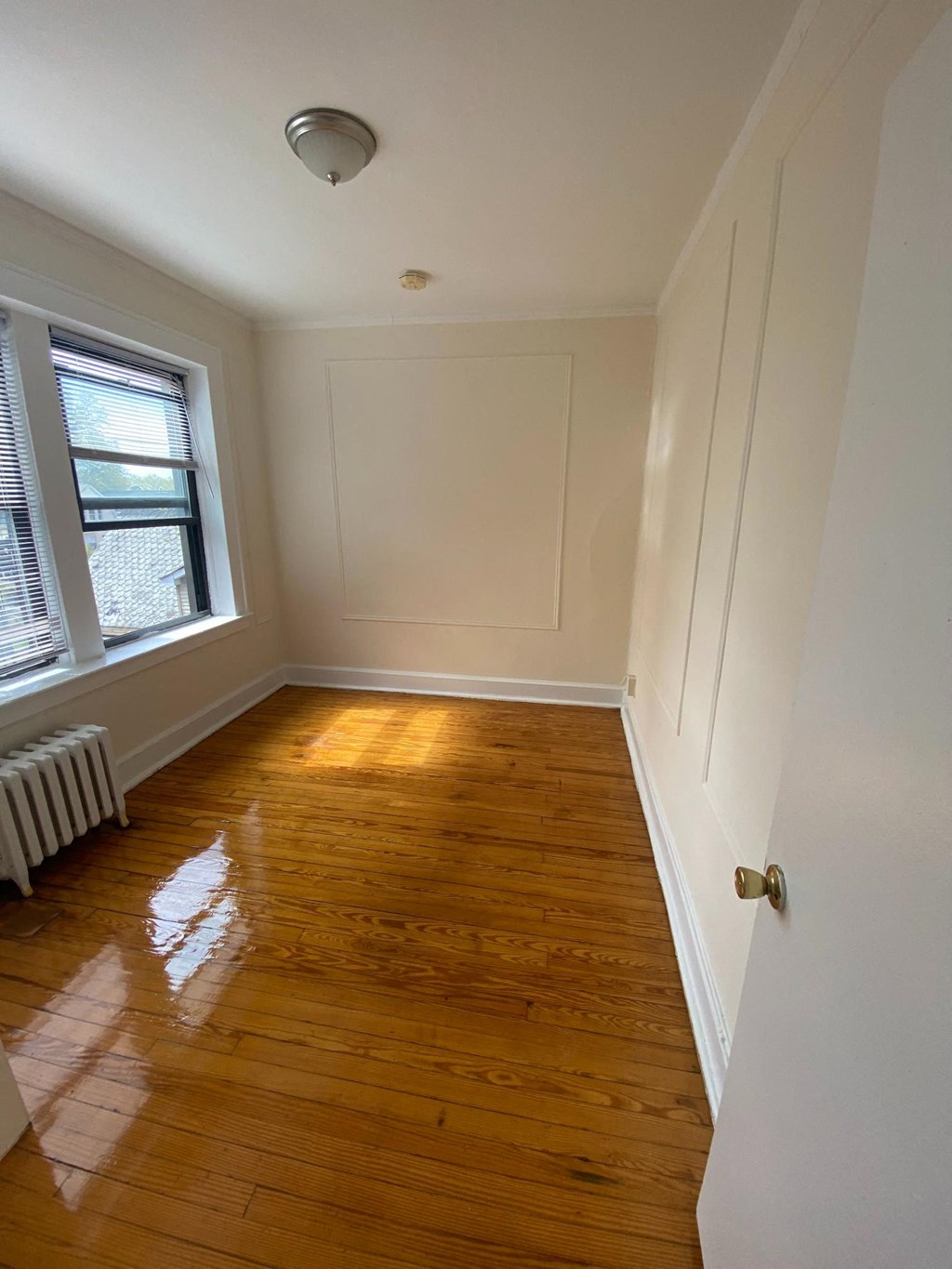 a small room with wooden floors and a window and white walls