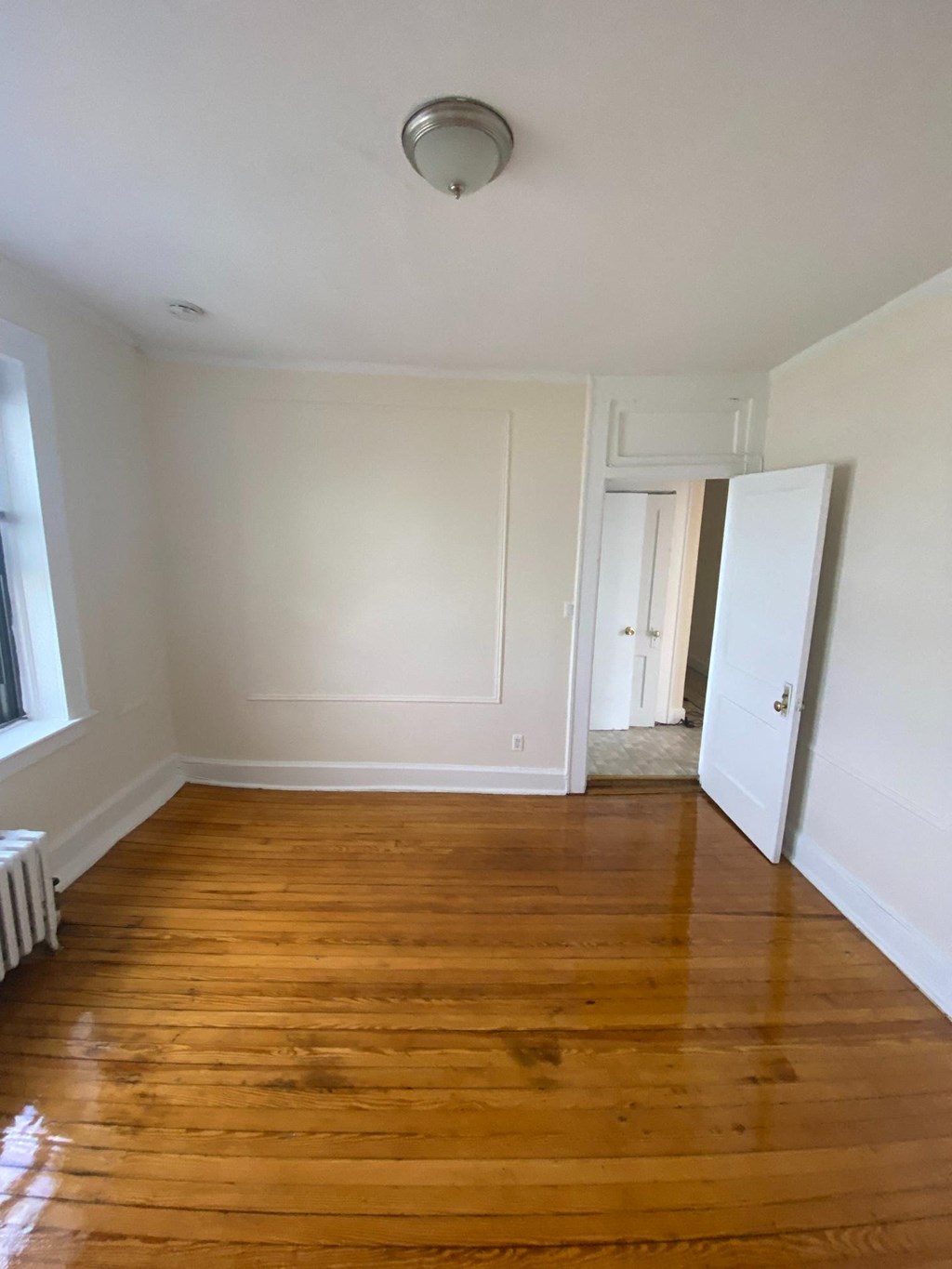an empty living room with wooden floors and white walls