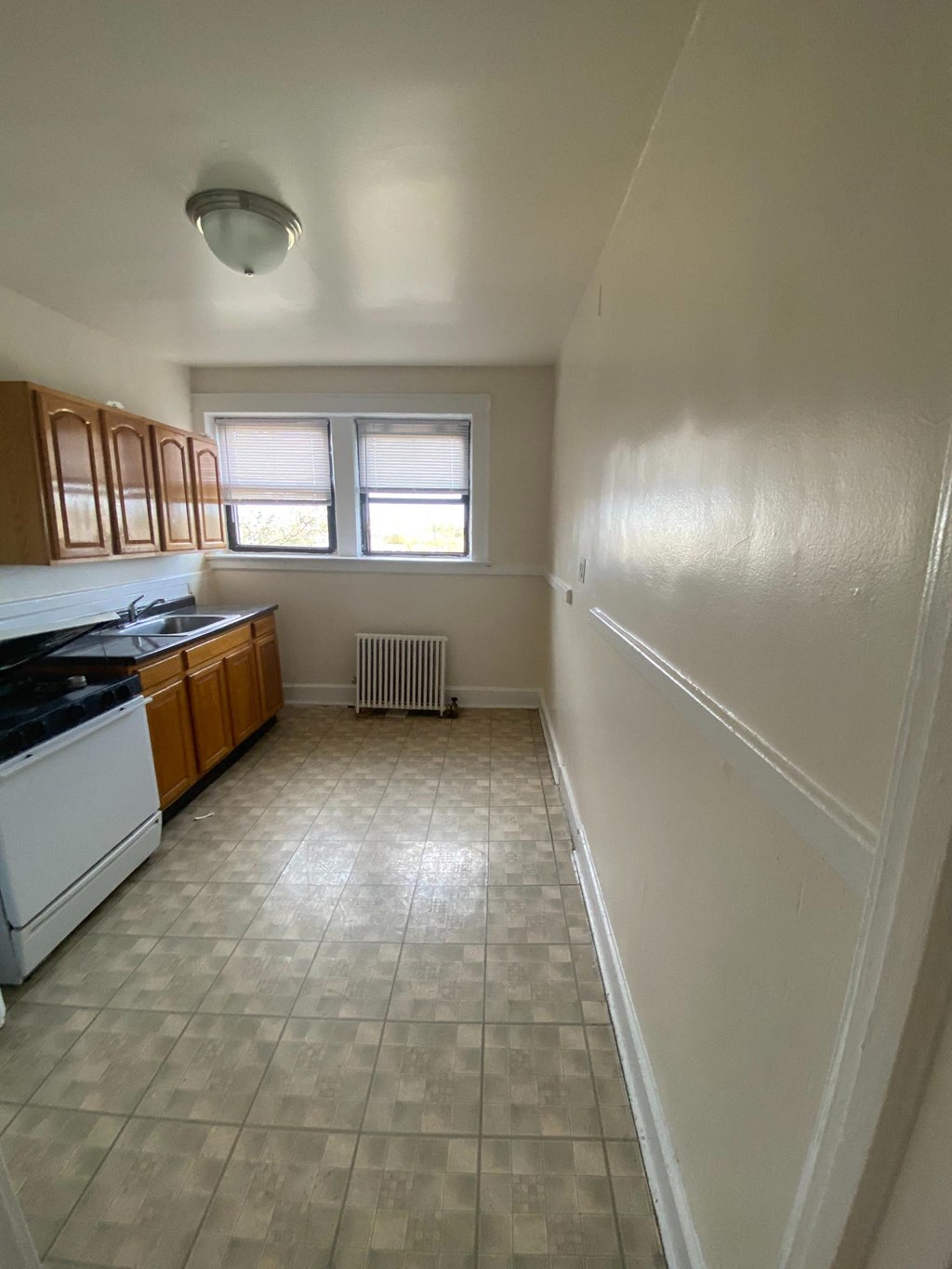an empty kitchen with white appliances and wooden cabinets