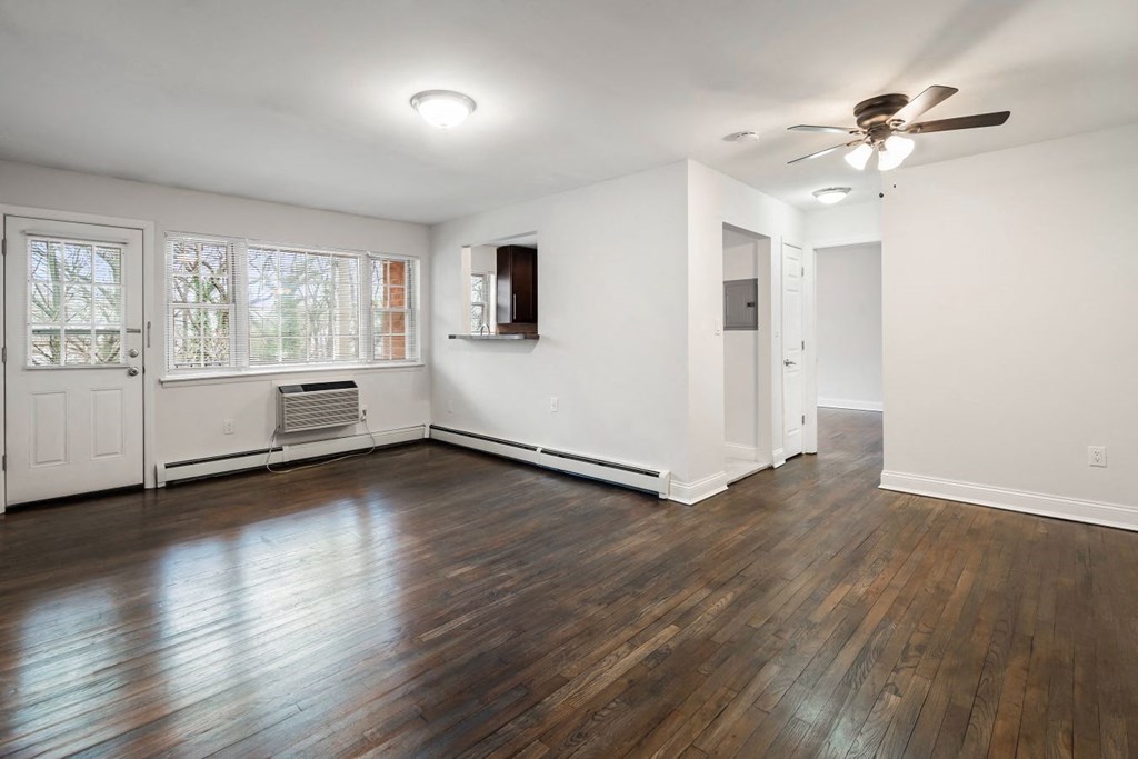 an empty living room with wood floors and a ceiling fan