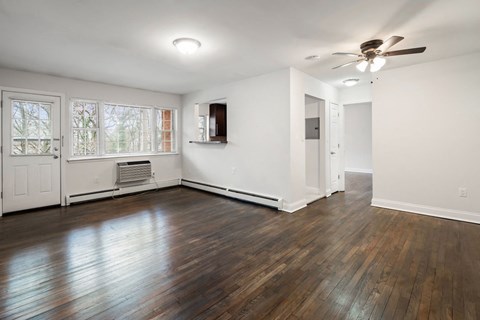 an empty living room with wood floors and a ceiling fan