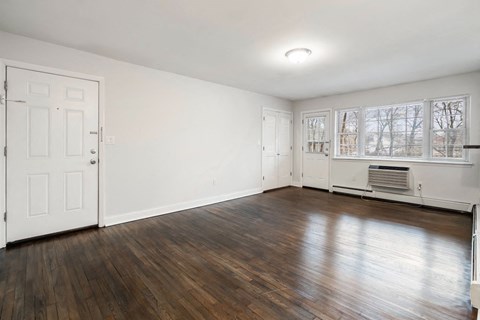 an empty living room with white walls and wood floors