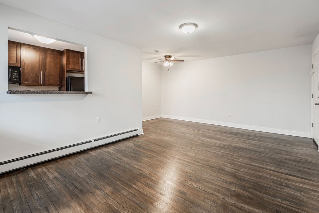 an empty living room with wood flooring and a ceiling fan