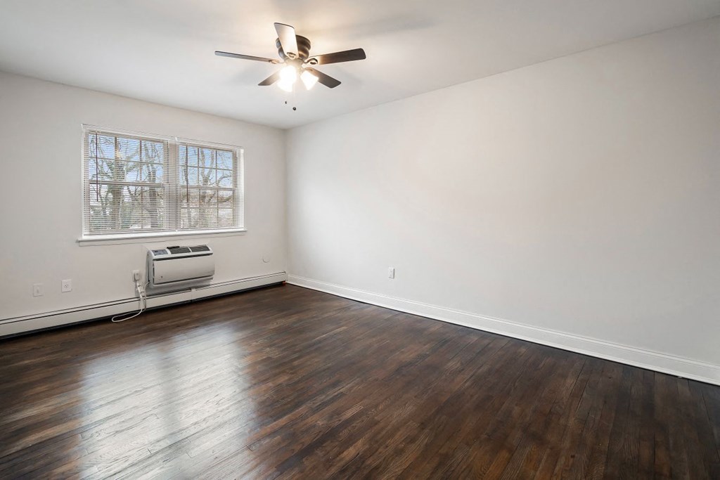 an empty living room with wood floors and a ceiling fan