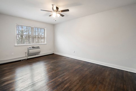 an empty living room with wood floors and a ceiling fan