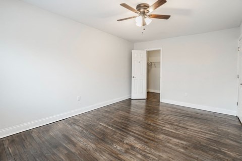 an empty living room with white walls and a ceiling fan