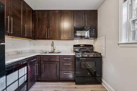 A kitchen with dark wood cabinets and black appliances.