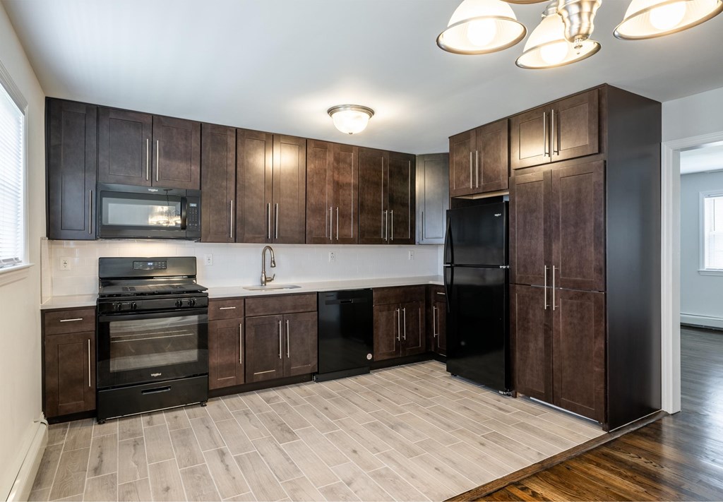 a kitchen with dark wood cabinets and black appliances