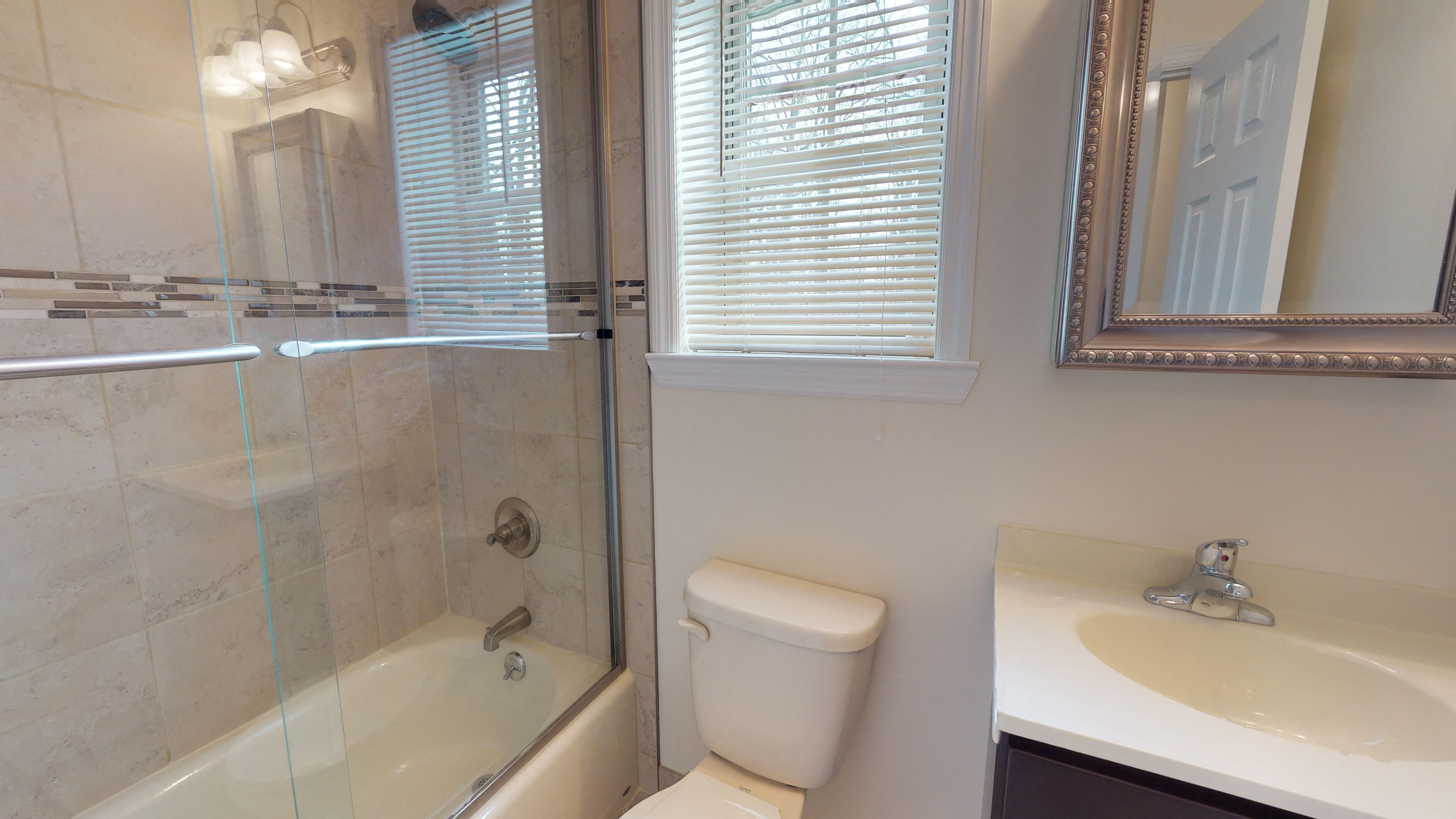 a bathroom with a shower toilet and sink and a mirror