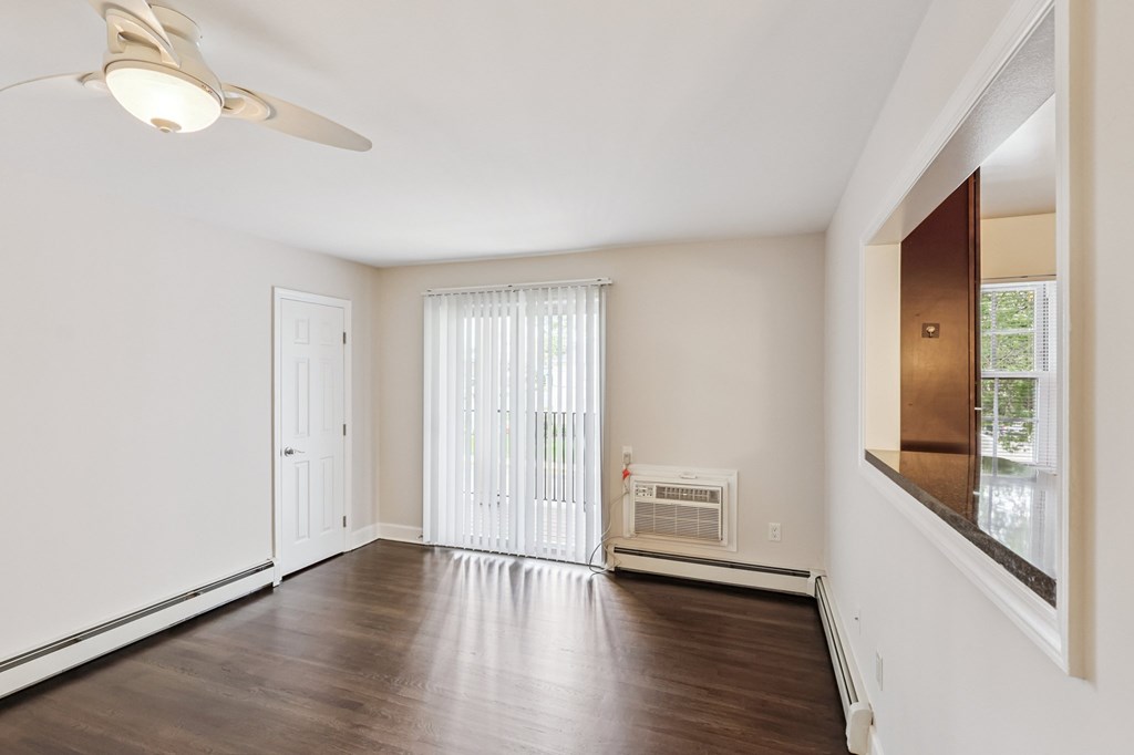 A room with a ceiling fan and a window with blinds.