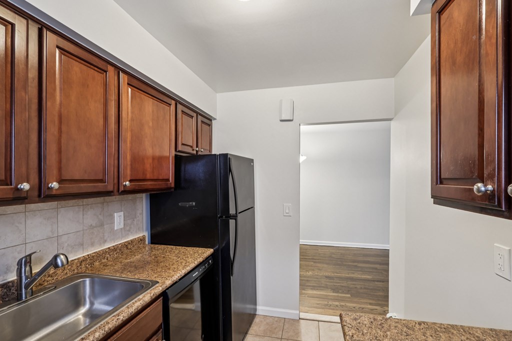 A kitchen with a black fridge and wooden cabinets.