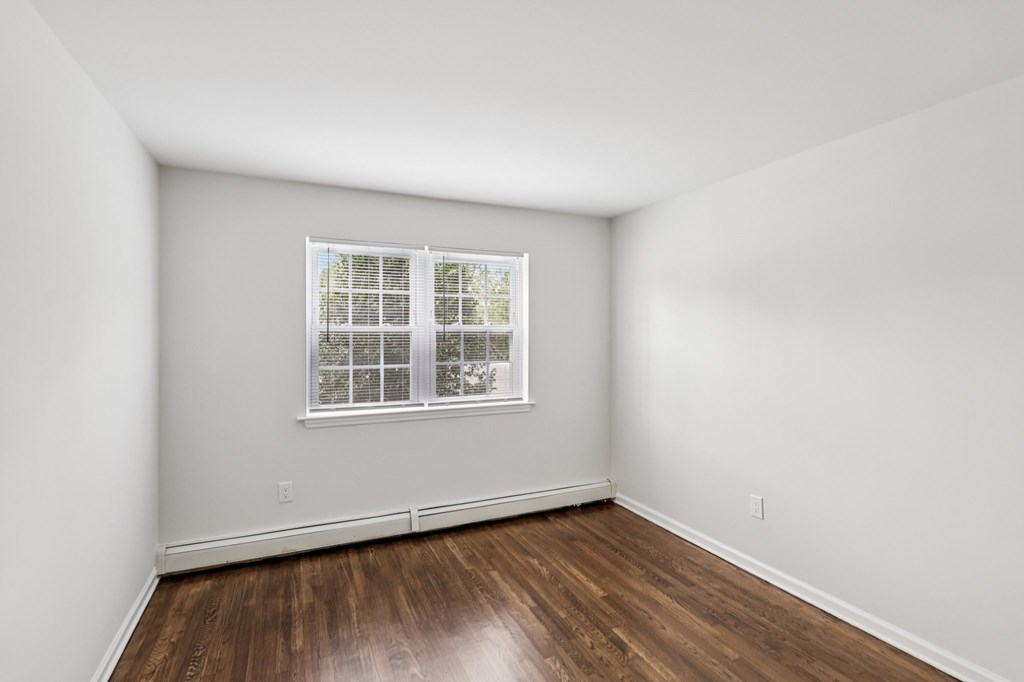 A room with a window and wooden floors.