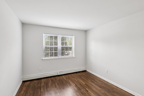 A room with a window and wooden floors.