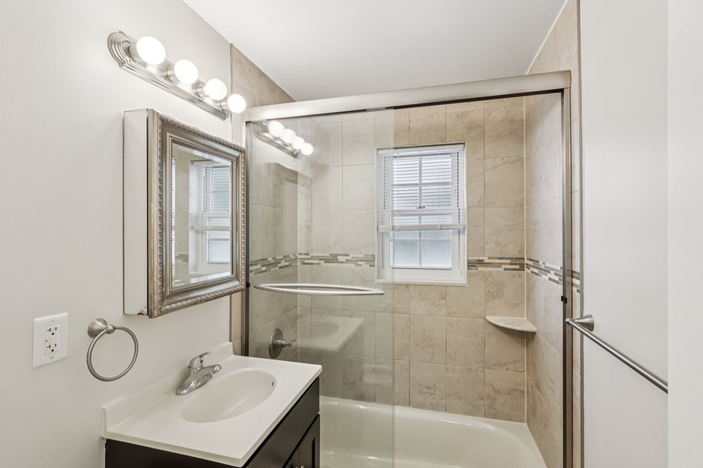 A bathroom with a sink, mirror, and shower.