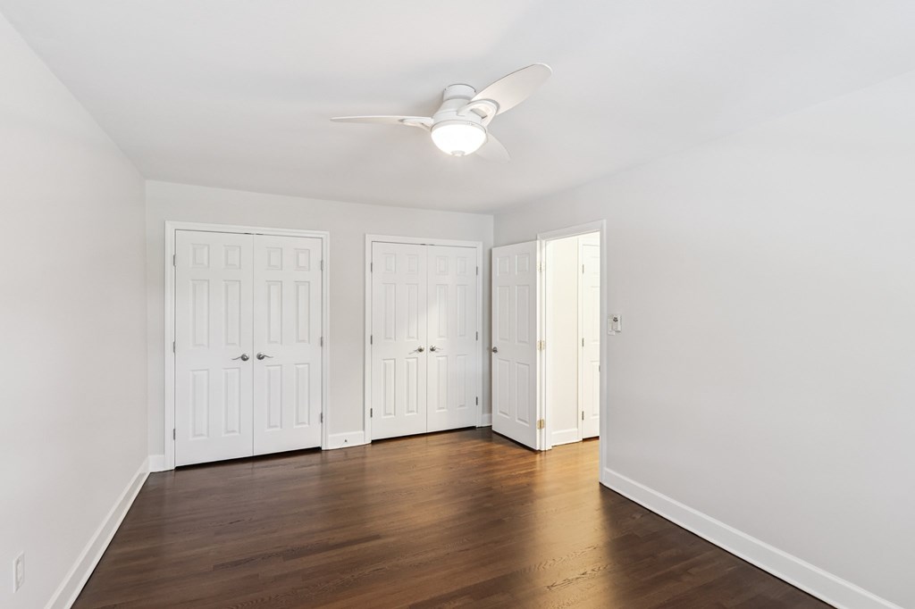 Three white doors are in a room with wood floors and a ceiling fan.