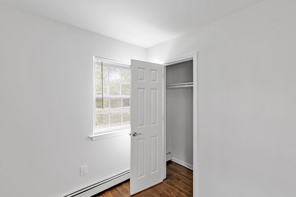 A white door is open in a room with a window.