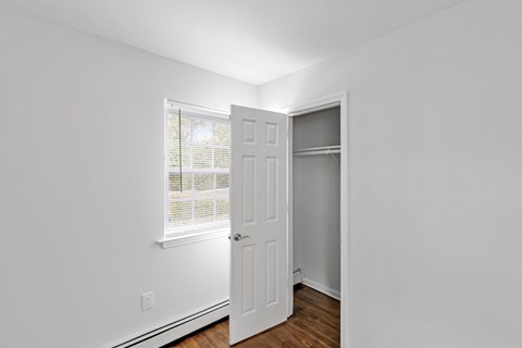 A white door is open in a room with a window.