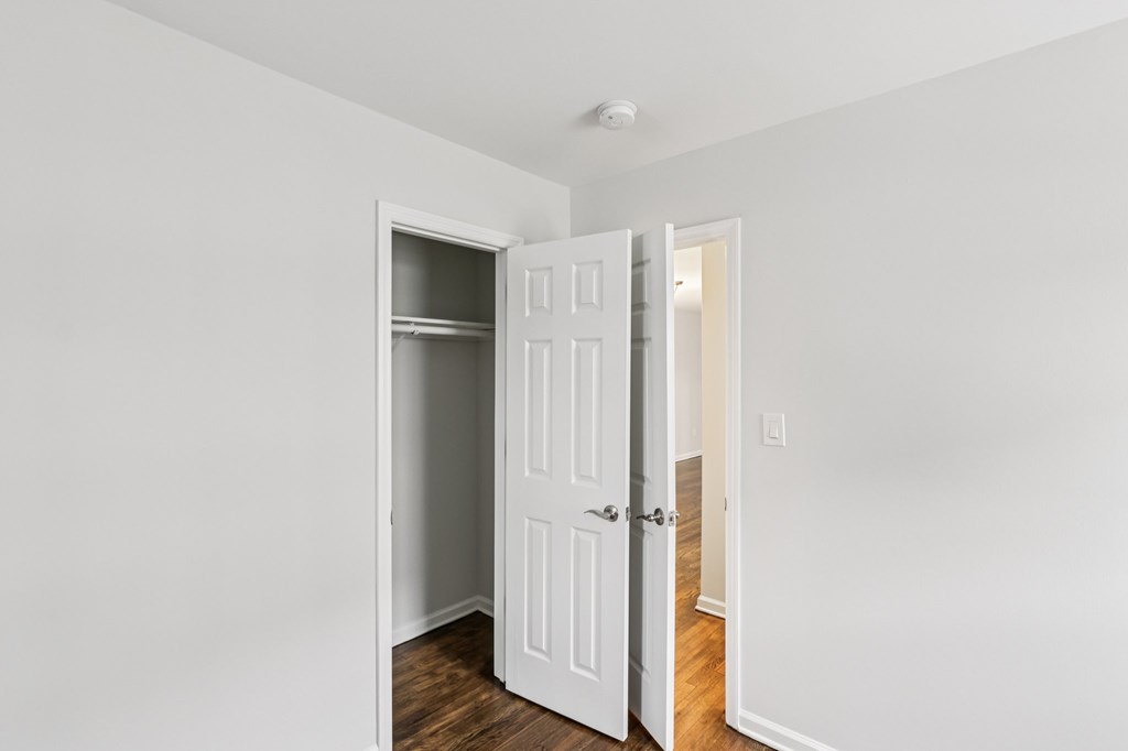 A white door is open to a room with a wooden floor.