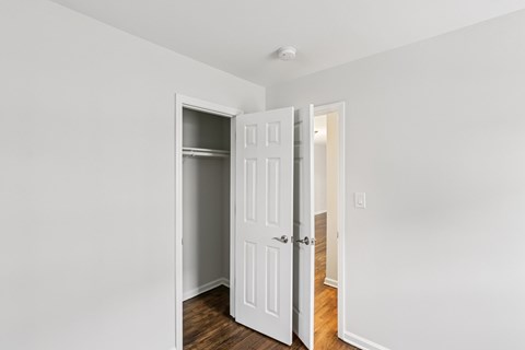 A white door is open to a room with a wooden floor.