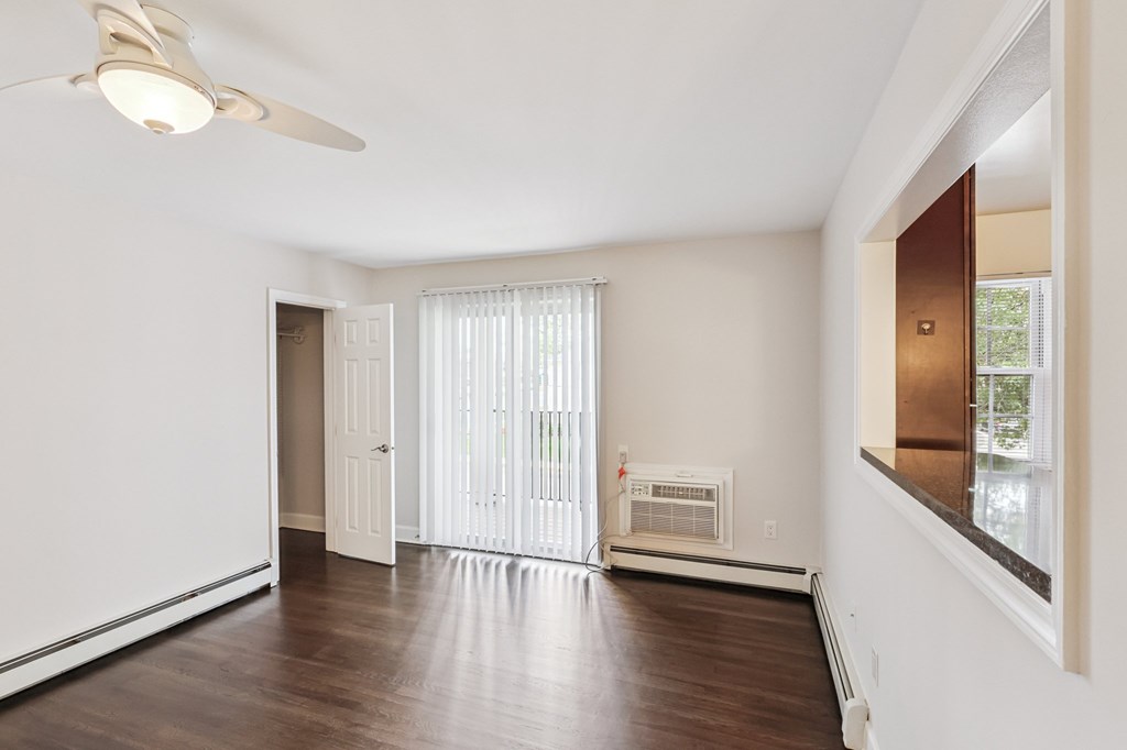 A room with a ceiling fan and a window with blinds.