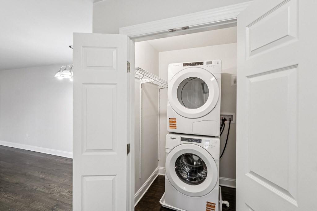 A white door is open to a room with a stack of washing machines.
