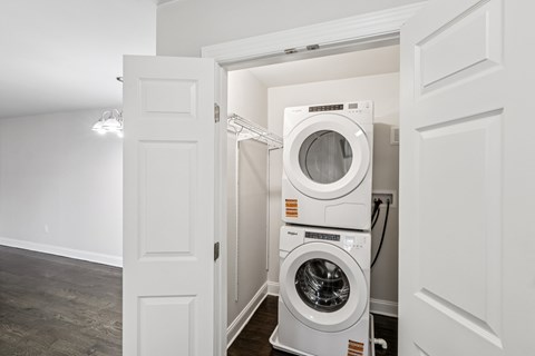 A white door is open to a room with a stack of washing machines.