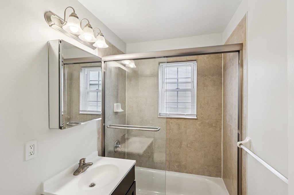 A bathroom with a sink, mirror, and shower.