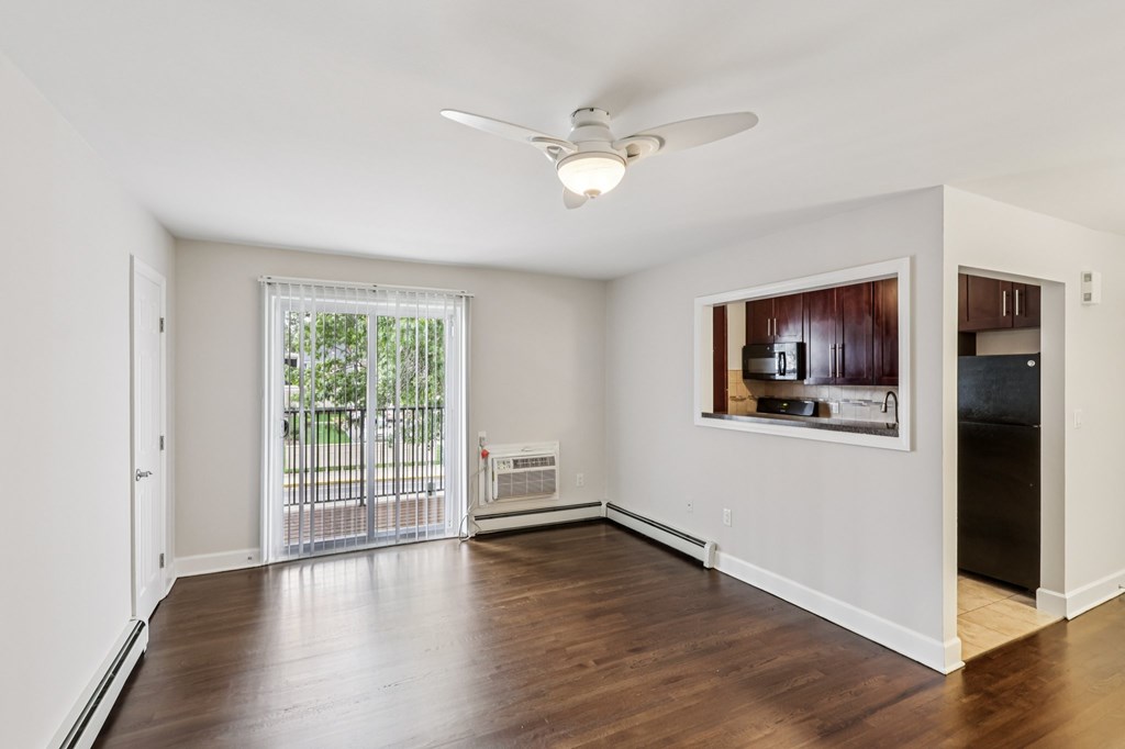 A room with a ceiling fan and a window with a view of a fence and trees.