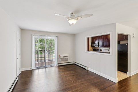 A room with a ceiling fan and a window with a view of a fence and trees.