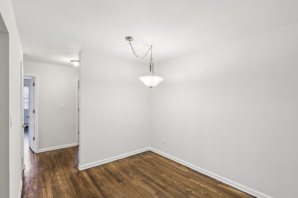 A room with a wooden floor and a chandelier hanging from the ceiling.
