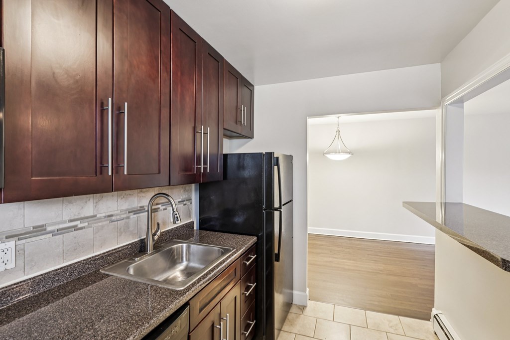 A kitchen with dark wood cabinets and a black refrigerator.