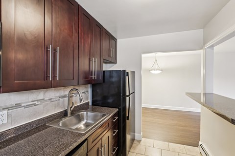 A kitchen with dark wood cabinets and a black refrigerator.