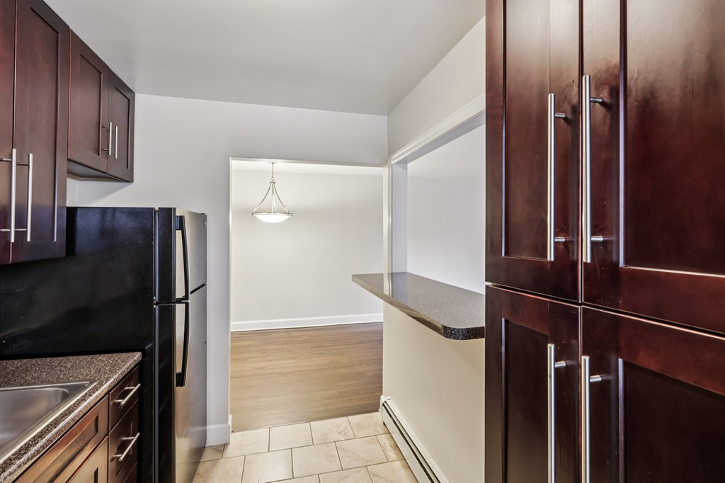 A kitchen with dark brown cabinets and a black refrigerator.