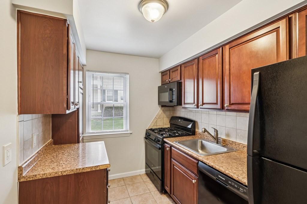 A kitchen with brown cabinets and black appliances.