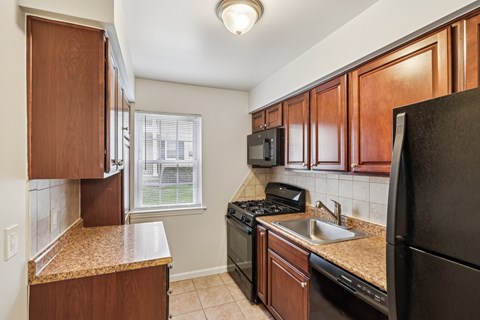 A kitchen with brown cabinets and black appliances.