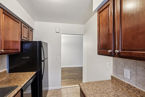 A kitchen with a black fridge and brown cabinets.