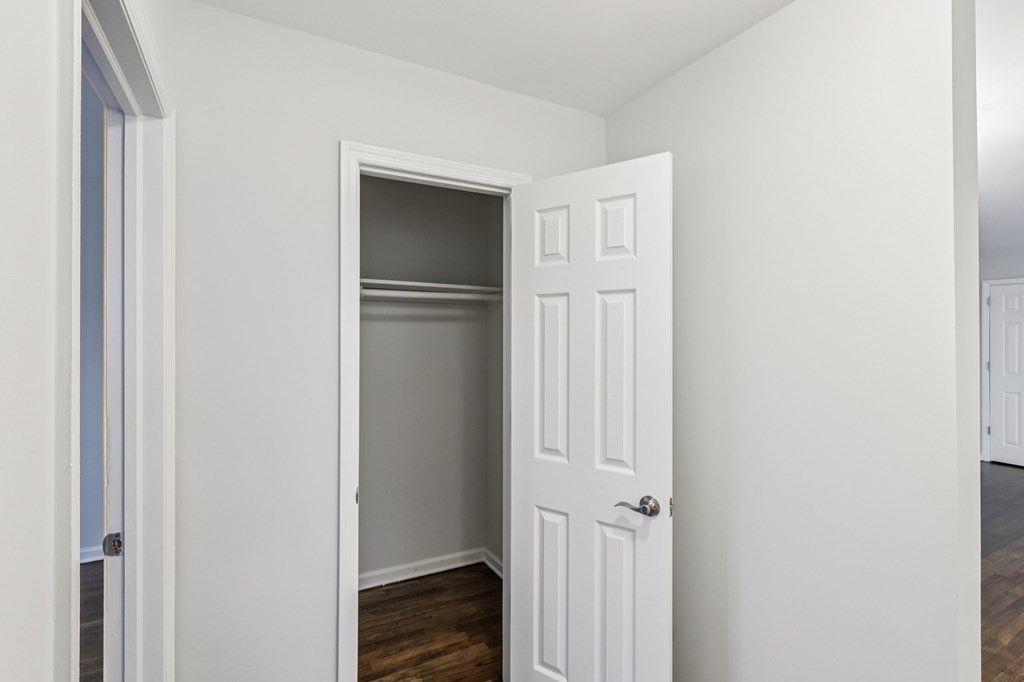 A white door is open to a room with a wooden floor.