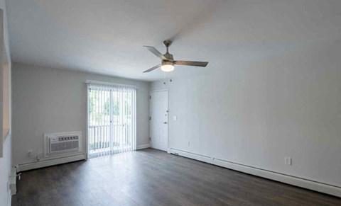 an empty living room with white walls and a ceiling fan