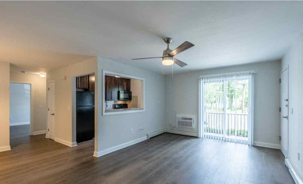 an empty living room with a ceiling fan and a window