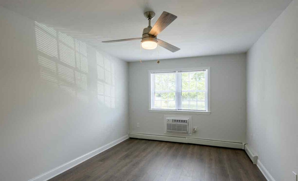 an empty living room with a ceiling fan and a window