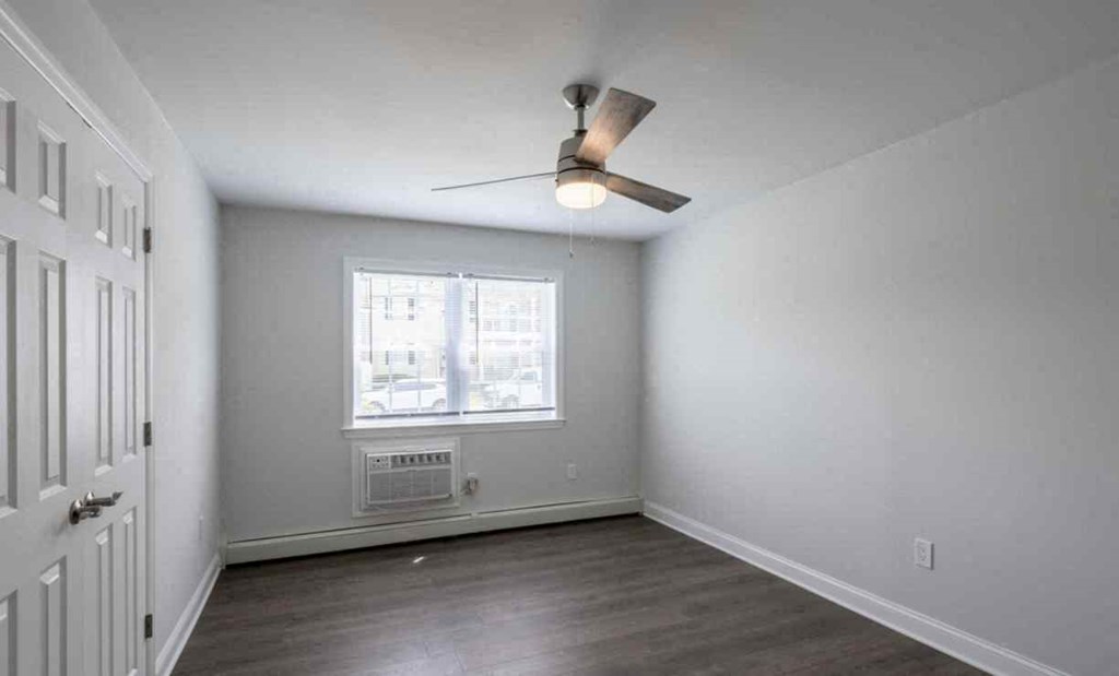 an empty living room with a ceiling fan and a window