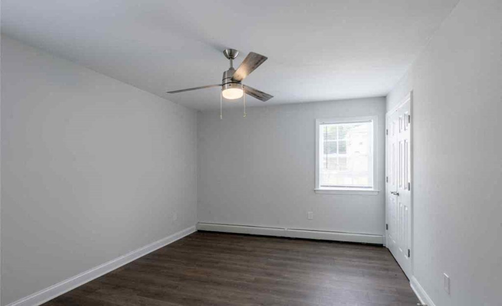 an empty room with white walls and a ceiling fan