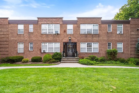 a red brick house with a green lawn in front of it
