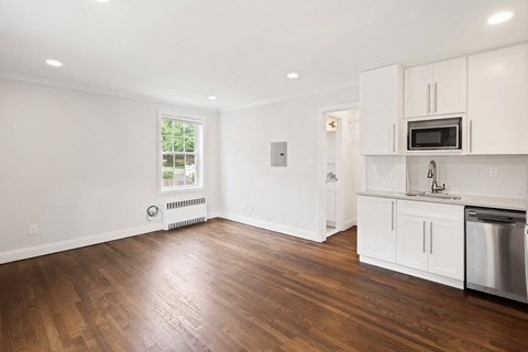 a living room with white cabinets and a kitchen with wood floors