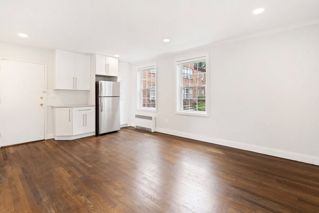 an empty living room with a refrigerator and a window