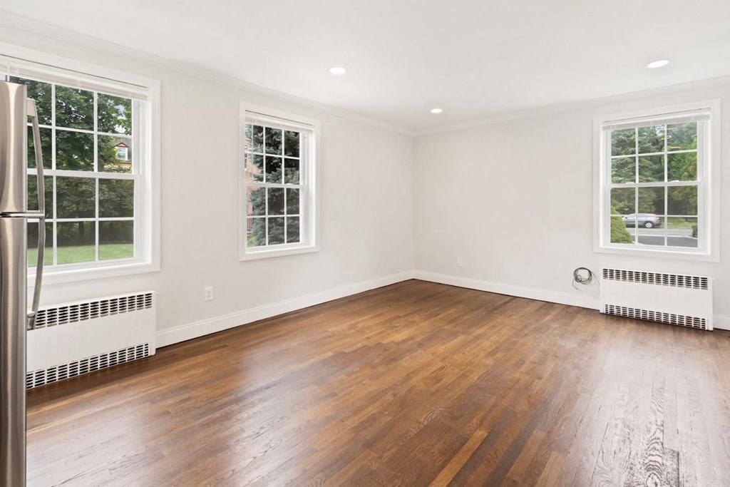 an empty living room with wood floors and two windows
