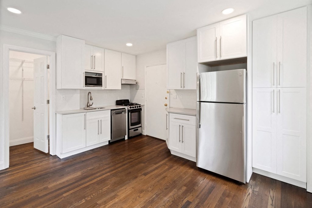 a white kitchen with stainless steel appliances and white cabinets
