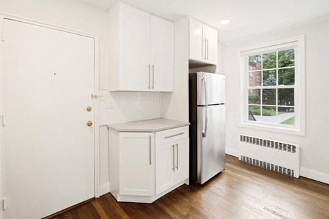 a small kitchen with white cabinets and a refrigerator