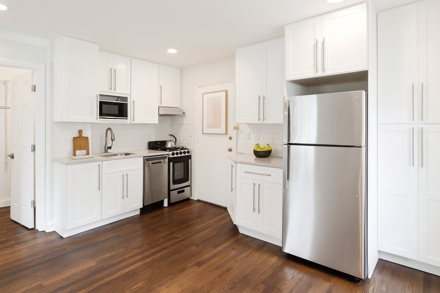 A kitchen with white cabinets and a stainless steel refrigerator.