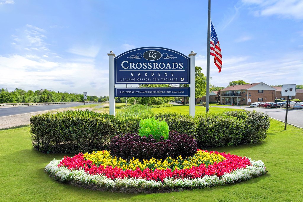 the sign for crossroads gardens in front of a flower garden